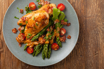 Roasted chicken breast, served on asparagus with tomato sauce, dried tomatoes. Top view.