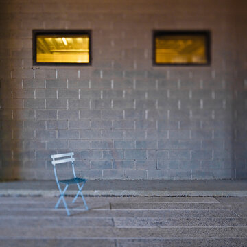 Folding chair in front of concrete block wall.