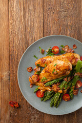 Roasted chicken breast, served on asparagus with tomato sauce, dried tomatoes. Top view.