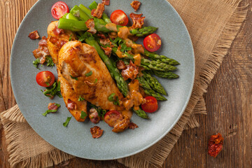 Roasted chicken breast, served on asparagus with tomato sauce, dried tomatoes. Top view.