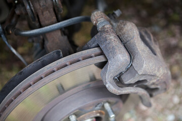 Rusty ventilated brake disk with used brake pads in calliper, close-up view