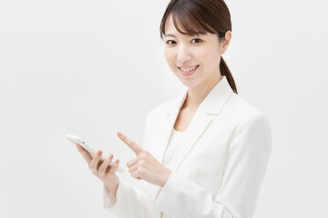 スマートフォンを持つ、白いスーツ姿の女性