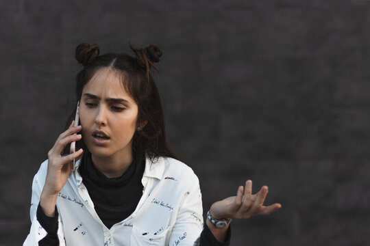 Girl Talking Business, With Mobile Phone In Her Ear, In Hand, Arguing, Angry, With Expressive Gesture, Pretty Woman, With Modern Hairstyle And Fashionable Clothes