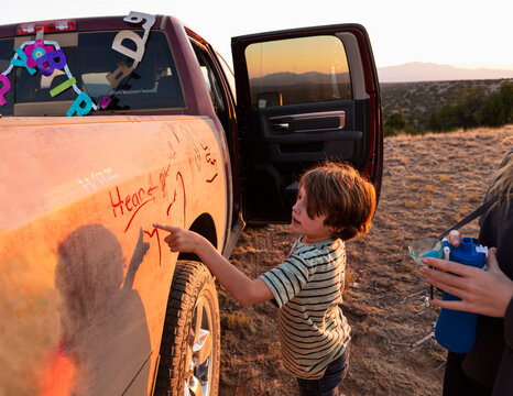 Two children painting the side of an old pickup truck