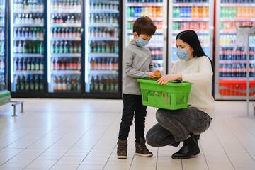Portrait of a mother and her little son wearing protective face mask at a supermarket during the coronavirus epidemic or flu outbreak. Empty space for text.