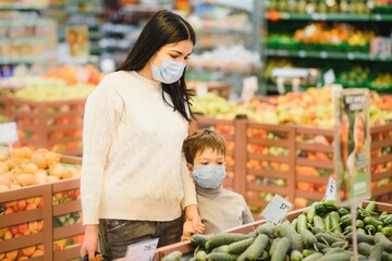 Young woman and her kid wearing protective face masks shop a food at a supermarket during the coronavirus epidemic or flu outbreak