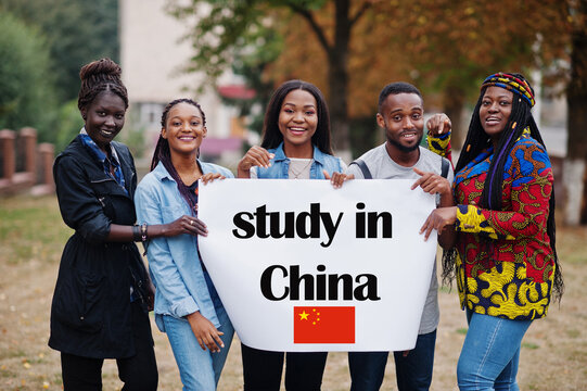 Study In China. Group Of Five African College Students On Campus At University Yard Hold White Blank. Abroad Countries For Student Concept.