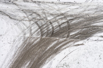 Tracks of car tires in thin layer of first snow in winter. Aerial view