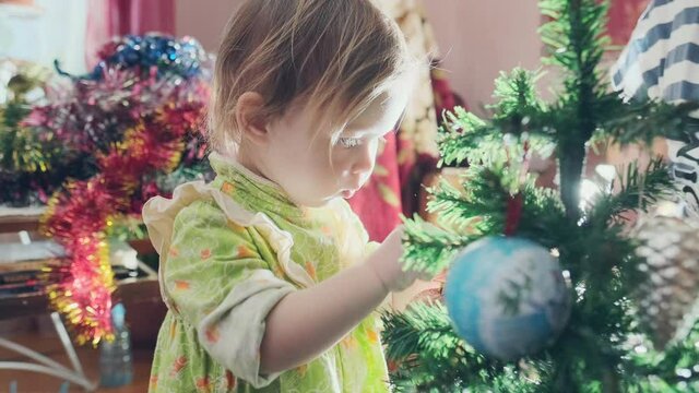 Baby and Christmas tree. Toddler girl decorates Christmas pine tree with her grandmother in real home environment