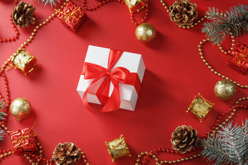 Box with a red bow around Christmas decorations on a red background.
