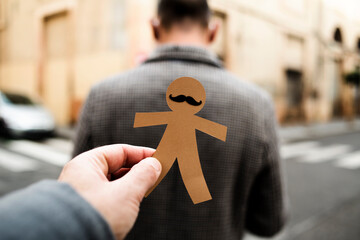 man about to stick a paper man doll to another man