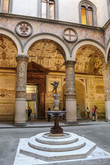 Fototapeta na wymiar Nice view of the first courtyard in the Palazzo Vecchio with a fountain by Battista del Tadda in the centre. A porphyry column holds a marble tub and on top is the bronze statue Putto with Dolphin.