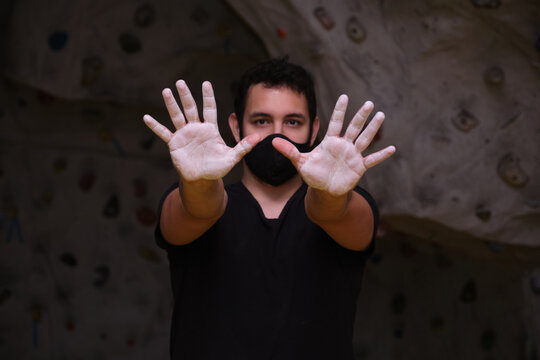 Man showing his hands smeared with magnesium powder to the camera. Climbing at a climbing wall. - Powered by Adobe