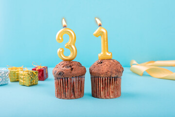 31 Number gold candle on a cupcake against a pastel blue background thirty first year celebration