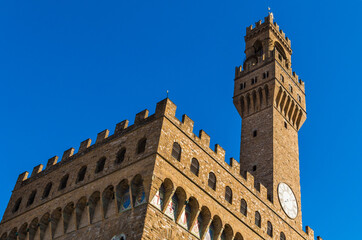 Fototapeta na wymiar Great close-up corner view of the famous cubical Palazzo Vecchio museum with the clock on the Arnolfo’s tower (Torre d'Arnolfo) in Florence, Italy. The façade is made of solid rusticated stonework.