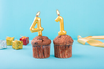 41 Number gold candle on a cupcake against a pastel blue background forty first year celebration