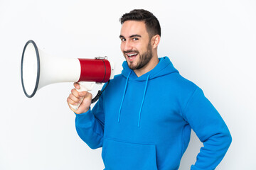Young caucasian handsome man isolated on white background holding a megaphone and smiling