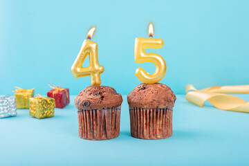 45 Number gold candle on a cupcake against a pastel blue background forty fifth year celebration