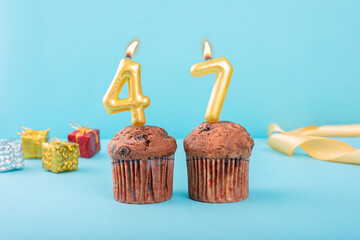 47 Number gold candle on a cupcake against a pastel blue background forty seventh year celebration
