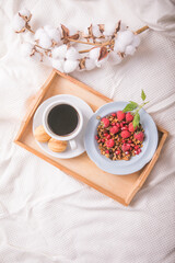 Breakfast in bed with coffee cup and granola on tray. Copy Space. Cozy breakfast. Man bringing woman breakfast in bed with theater tickets to celebrate wedding anniversary