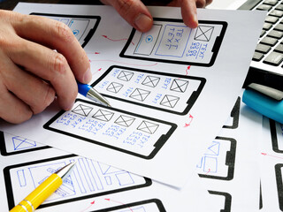 UX designer works with sketches of the mobile app and website.