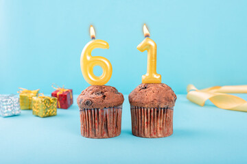 61 Number gold candle on a cupcake against a pastel blue background sixty one year celebration