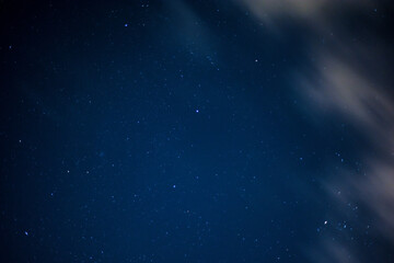 Fototapeta na wymiar View of stars in a clear night sky with motion in clouds moving acroos the sky above