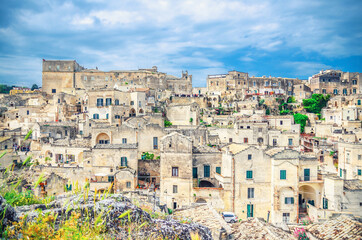 Fototapeta na wymiar Sassi di Matera panoramic view of historical centre Sasso Caveoso of old ancient town with rock cave houses, blue sky and white clouds, UNESCO World Heritage, Basilicata, Southern Italy