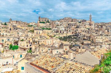 Fototapeta na wymiar Sassi di Matera old ancient town, aerial panoramic view of historical centre Sasso Caveoso with rock cave houses, blue sky and white clouds, UNESCO World Heritage, Basilicata, Southern Italy