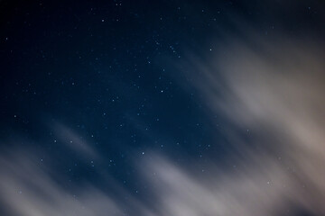 Fototapeta na wymiar View of stars in a clear night sky with motion in clouds moving acroos the sky above