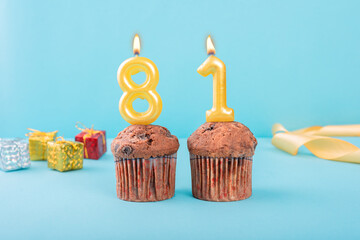 81 Number gold candle on a cupcake against a pastel blue background eighty one year celebration