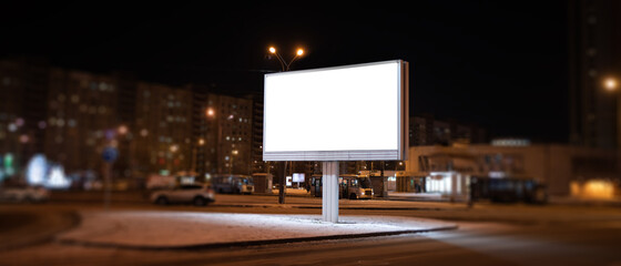 Advertising billboard at night with white advertising field in the middle of the road