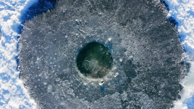 Winter swim. Young man jumps into winter lake at sunny day. Multi camera scene. Camera 3. Aerial, top down view