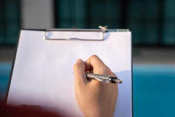 Action of an engineer is writing down on the clipboard paper to verify the quality of new house...