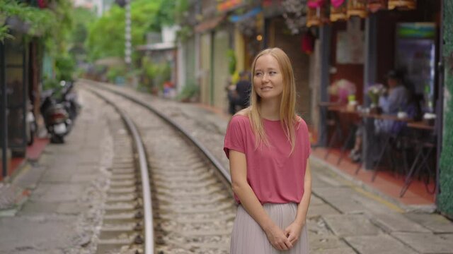 Young woman traveler explores the area of the Hanoi city where railway paths go through a residential area. Hanoi Train Street is a famous tourist destination