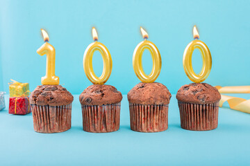 1000 Number gold candle on a cupcake against a pastel blue background one thousand year celebration