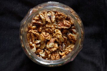 Orzechy włoskie w dużym szklanym słoju na ciemnym tle