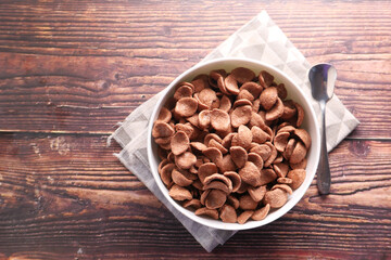  Top view of chocolate corn flakes in a bowl on wooden background 