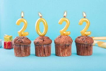 2022 Number gold candle on a cupcake against a pastel blue background two thousand and twenty two...