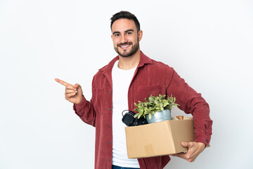 Young caucasian man making a move while picking up a box full of things isolated on white...