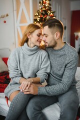 Romantic couple in love feeling happiness about their romance spending christmas eve together, woman and man enjoying perfect relationships and spending winter vacations in cozy home interior