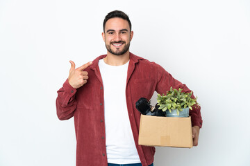 Young caucasian man making a move while picking up a box full of things isolated on white...