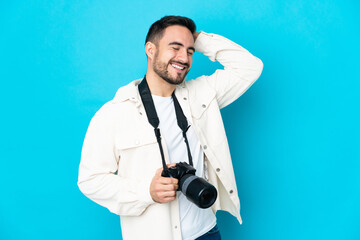 Young photographer man isolated on blue background smiling a lot