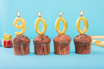 9000 Number gold candle on a cupcake against a pastel blue background nine thousand year celebration