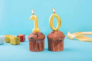 10 Number gold candle on a cupcake against a pastel blue background ten year celebration 