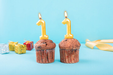 11 Number gold candle on a cupcake against a pastel blue background eleven year celebration