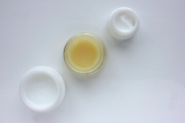 Facial cream on white background. Flat lay composition with variety of face cream in glass jars. Copy space