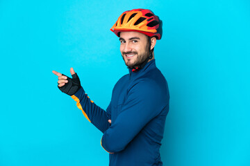 Young cyclist man isolated on blue background pointing finger to the side - obrazy, fototapety, plakaty