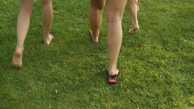 Women walking on grass barefoot and in flip-flops