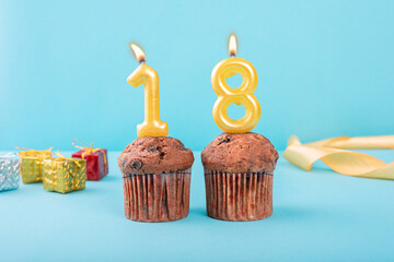 18 Number gold candle on a cupcake against a pastel blue background eighteen year celebration